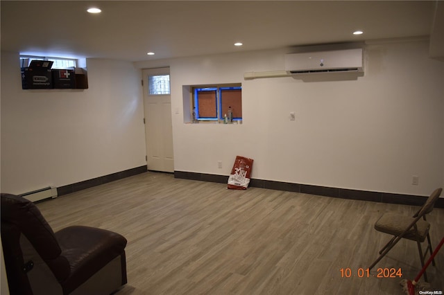 sitting room featuring hardwood / wood-style flooring, an AC wall unit, and a baseboard heating unit