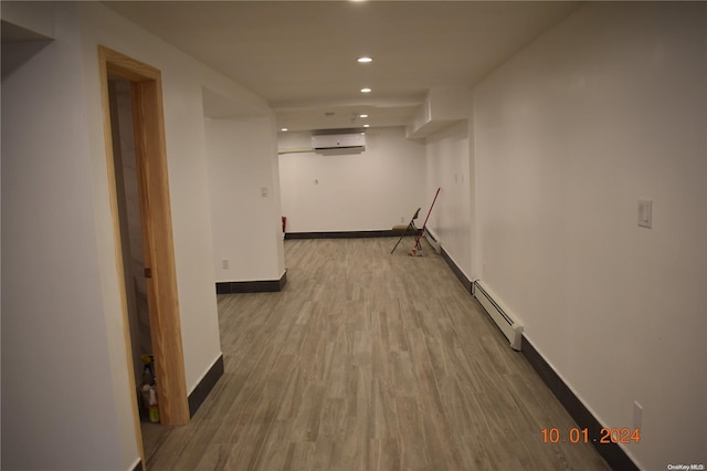 corridor featuring light wood-type flooring, baseboard heating, and a wall unit AC