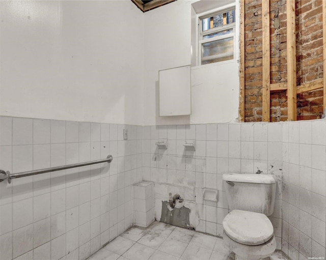 475 W 140th St, New York Manhattan, NY 10031 - bathroom with tile walls, toilet, marble look tiles, and wainscoting