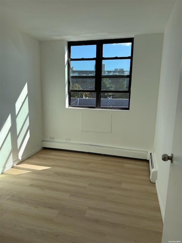 empty room with baseboard heating and light wood-type flooring