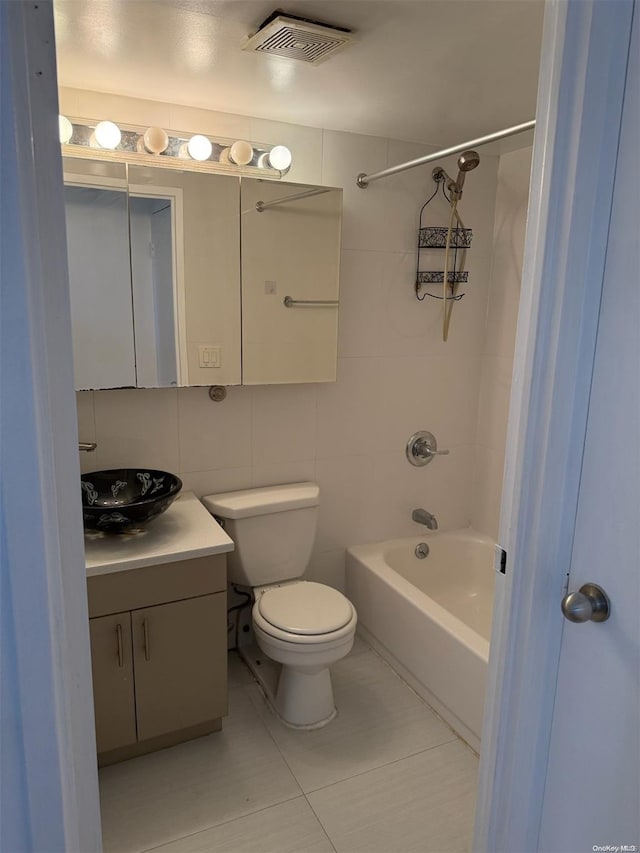 full bathroom featuring tiled shower / bath combo, tile patterned flooring, toilet, vanity, and tile walls