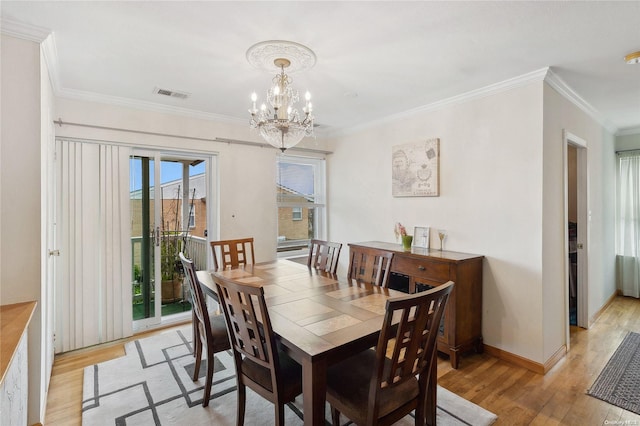 dining space featuring a chandelier, light wood-type flooring, and crown molding