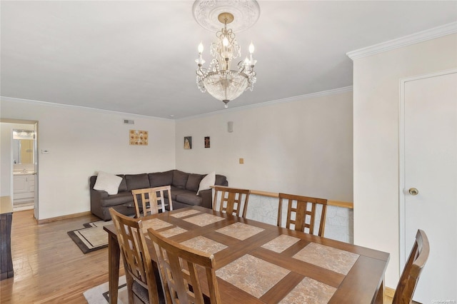 dining room featuring light hardwood / wood-style flooring, a chandelier, and ornamental molding