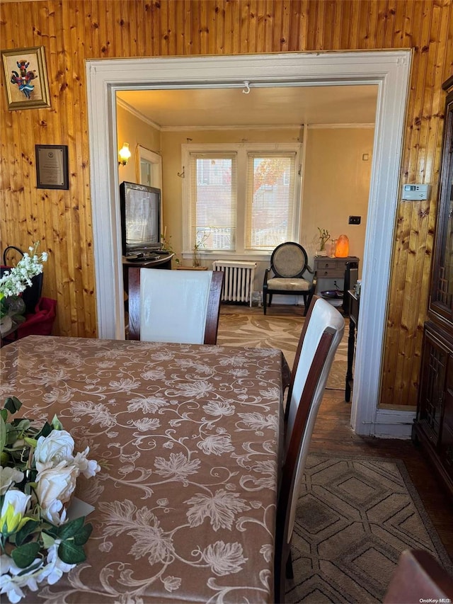 dining area featuring radiator heating unit, crown molding, and wooden walls