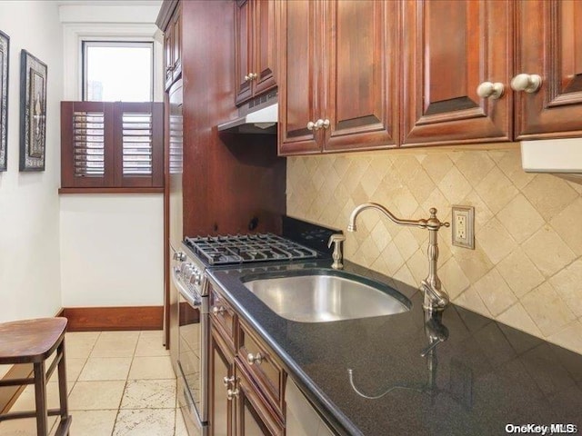 kitchen featuring stainless steel gas range, sink, light tile patterned floors, dark stone countertops, and decorative backsplash