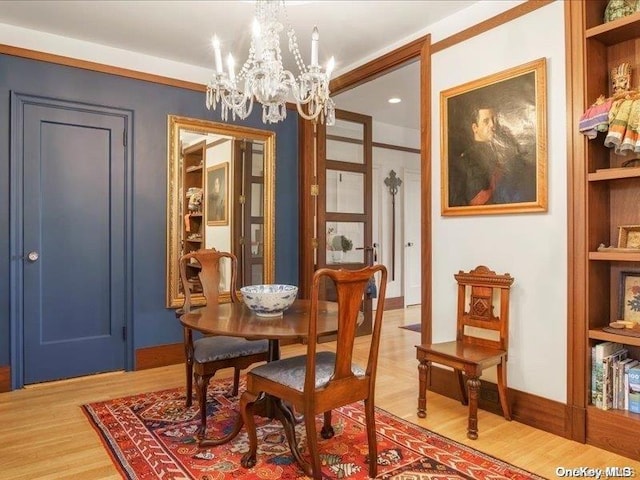 dining room featuring built in shelves, an inviting chandelier, and hardwood / wood-style floors