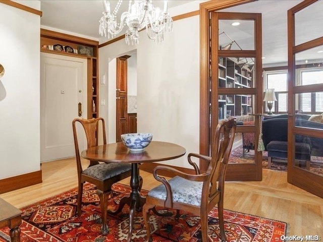 dining space with an inviting chandelier, light hardwood / wood-style flooring, and ornamental molding