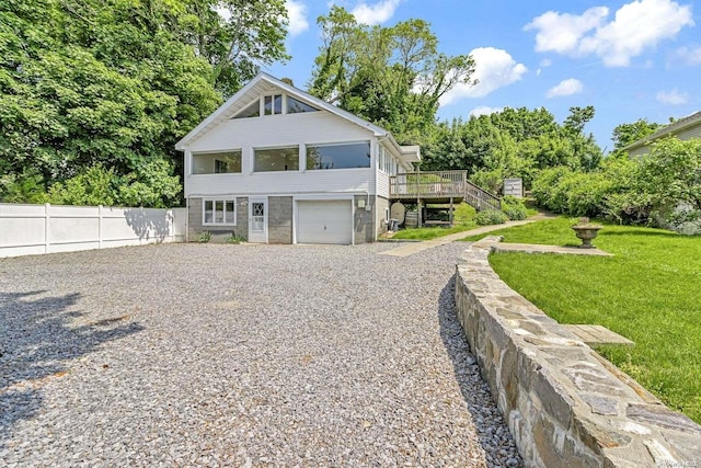 view of front of house featuring a garage, a wooden deck, and a front lawn