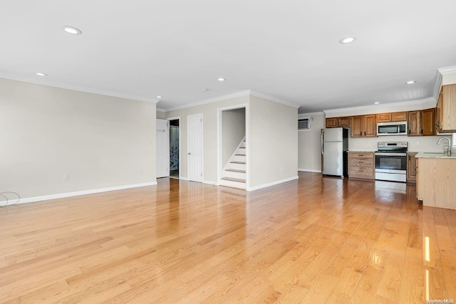 unfurnished living room featuring crown molding, sink, and light hardwood / wood-style floors