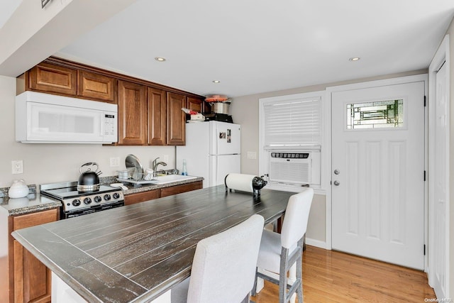 kitchen with sink, cooling unit, white appliances, a kitchen island, and light wood-type flooring