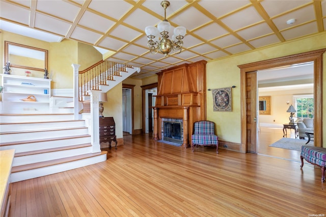 75 Oak Neck Ln, West Islip, NY 11795 - unfurnished living room with stairs, light wood-style floors, a large fireplace, and a chandelier