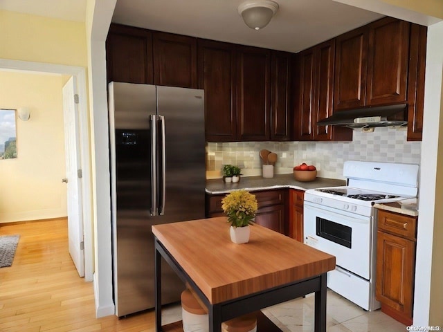 kitchen with tasteful backsplash, light wood-type flooring, stainless steel refrigerator with ice dispenser, and gas range gas stove