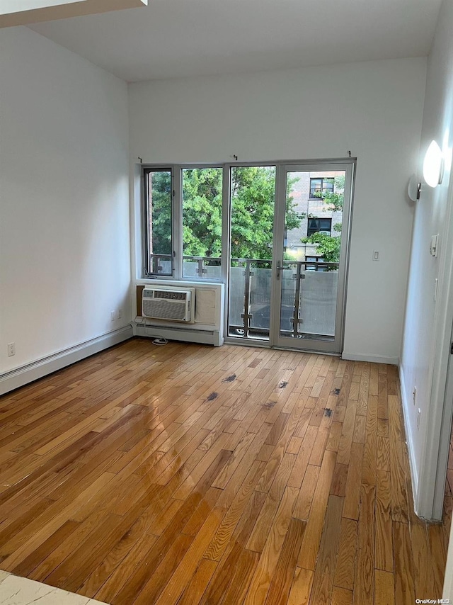 unfurnished room featuring plenty of natural light, a wall unit AC, and light hardwood / wood-style flooring