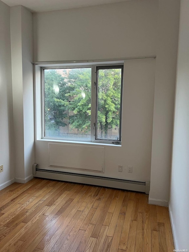 unfurnished room featuring light wood-type flooring and baseboard heating