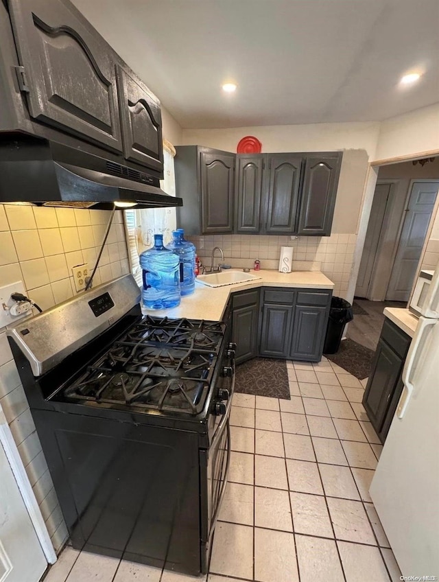 kitchen featuring backsplash, stainless steel range with gas cooktop, sink, and light tile patterned floors