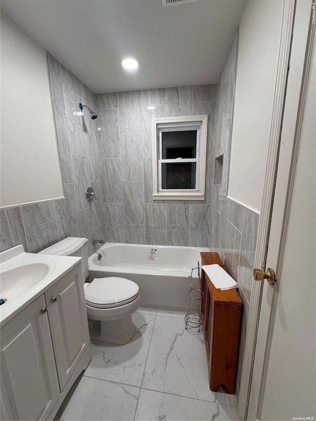 full bathroom with vanity, toilet, tile walls, and tiled shower / bath combo