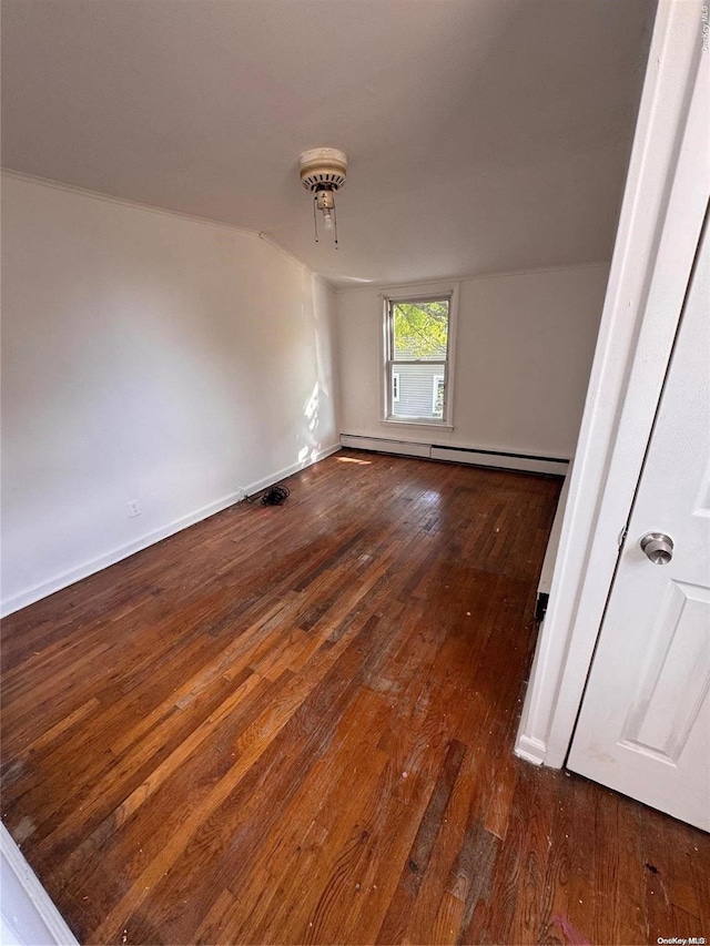 empty room with baseboard heating, dark hardwood / wood-style flooring, and vaulted ceiling