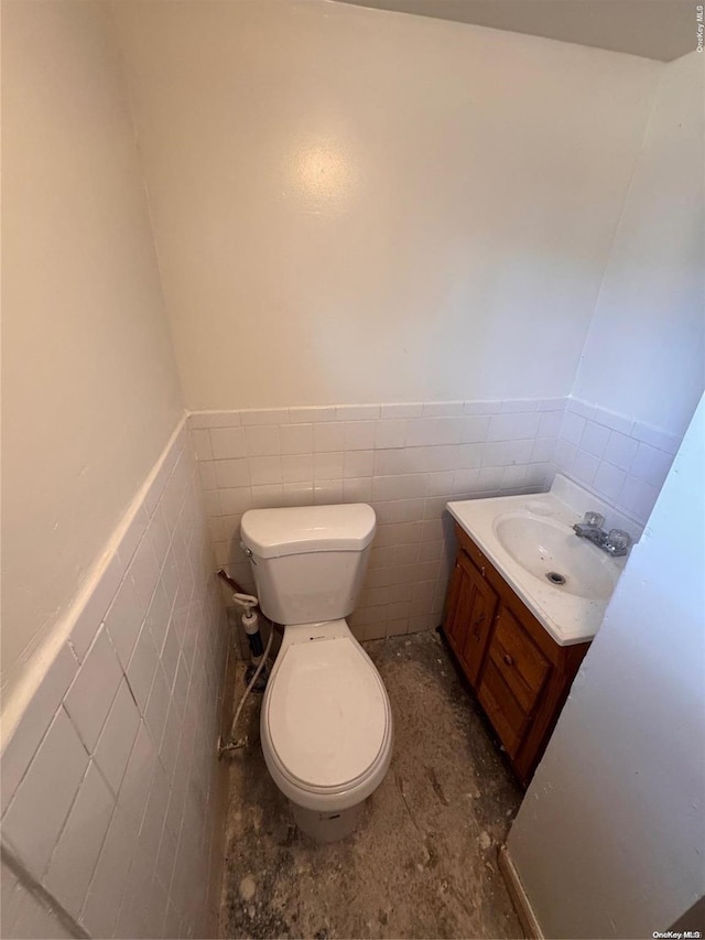 bathroom with vanity, toilet, and tile walls