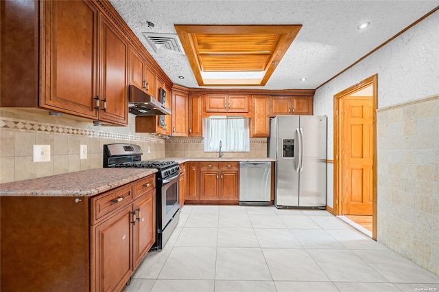 kitchen with light stone countertops, sink, a textured ceiling, light tile patterned flooring, and appliances with stainless steel finishes