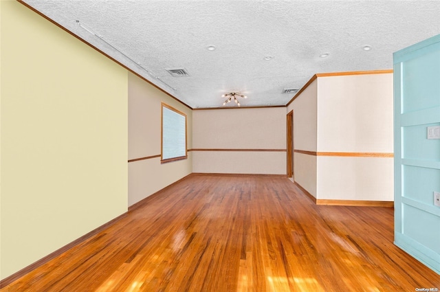 unfurnished room with ornamental molding, a textured ceiling, and light wood-type flooring