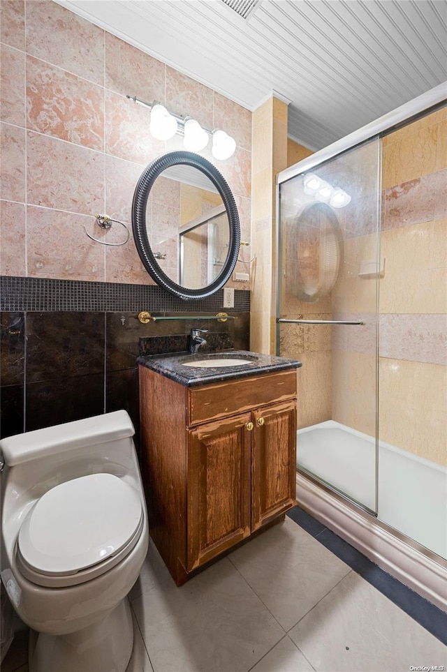 bathroom with walk in shower, tile patterned floors, toilet, vanity, and tile walls