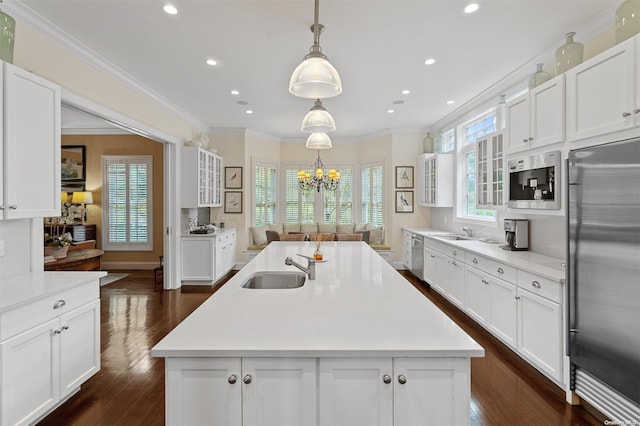 kitchen featuring a kitchen island with sink, crown molding, sink, pendant lighting, and built in appliances