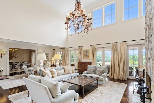 living room featuring french doors, an inviting chandelier, dark hardwood / wood-style floors, crown molding, and a towering ceiling