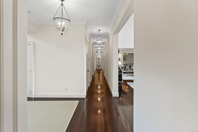 hall with a chandelier, dark hardwood / wood-style floors, and ornamental molding