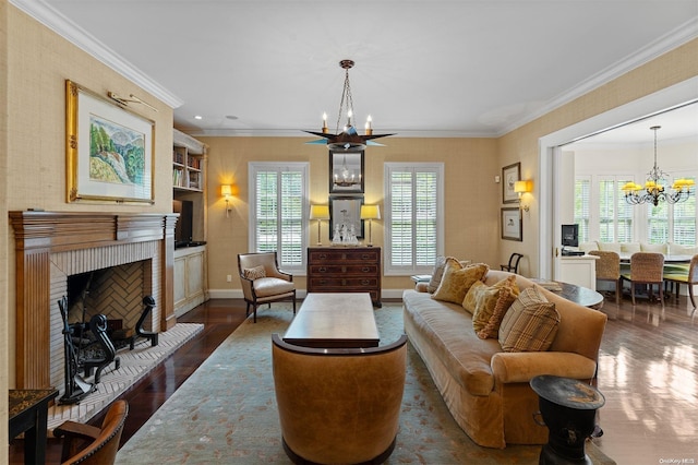 living room with a notable chandelier, dark hardwood / wood-style floors, ornamental molding, and a brick fireplace