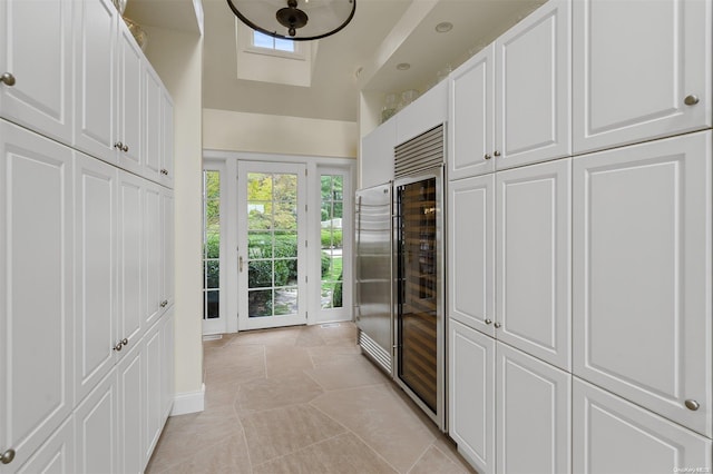 kitchen with white cabinets, light tile patterned floors, and beverage cooler