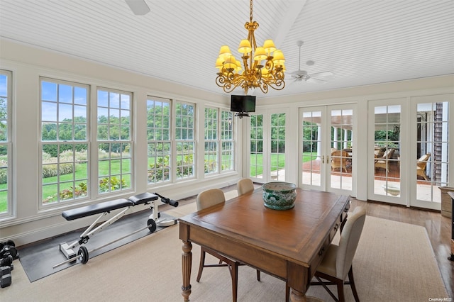 sunroom / solarium with plenty of natural light, ceiling fan with notable chandelier, and french doors