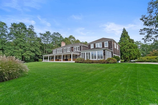 back of property with a lawn and covered porch