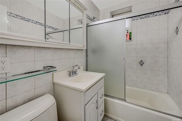 full bathroom featuring combined bath / shower with glass door, toilet, decorative backsplash, vanity, and tile walls