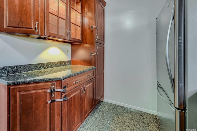 kitchen with stainless steel fridge and dark stone countertops