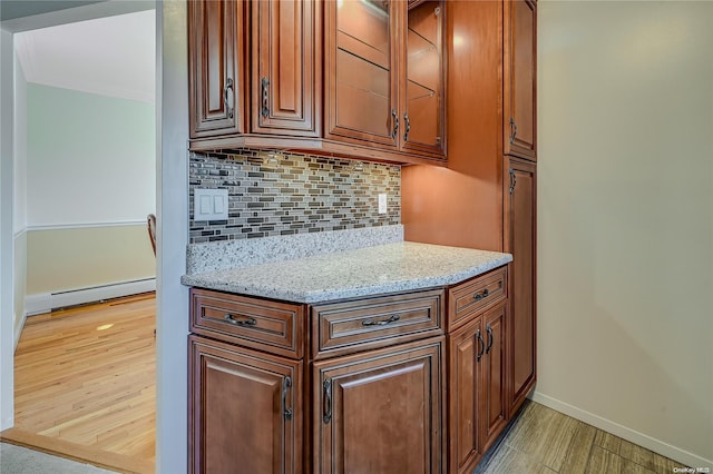 kitchen featuring light stone countertops, decorative backsplash, a baseboard radiator, and light hardwood / wood-style flooring