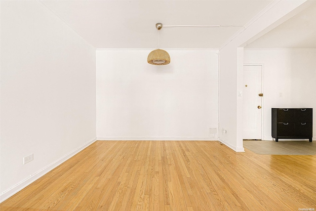 empty room featuring light wood-type flooring and ornamental molding