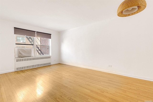 empty room featuring radiator heating unit and light hardwood / wood-style flooring