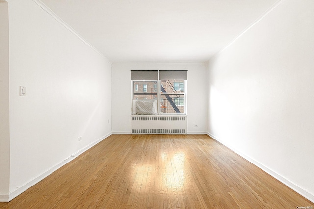 unfurnished room featuring wood-type flooring, radiator heating unit, and ornamental molding