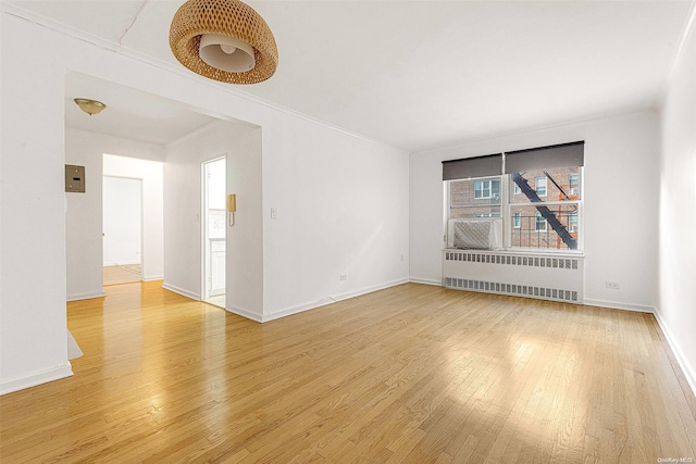 spare room with radiator heating unit, ornamental molding, and hardwood / wood-style flooring