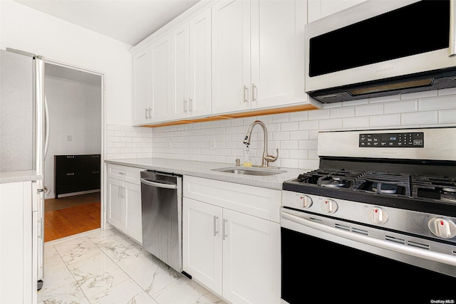 kitchen featuring stainless steel appliances, white cabinetry, tasteful backsplash, and sink