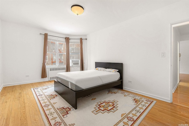 bedroom featuring radiator heating unit, cooling unit, and hardwood / wood-style floors