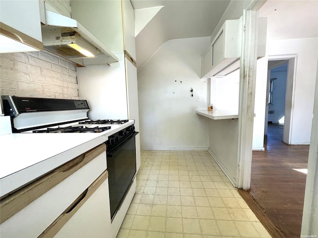 kitchen featuring under cabinet range hood, white cabinets, light countertops, gas range, and light floors