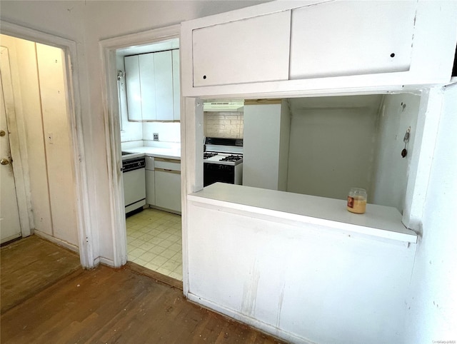 kitchen with wood finished floors, gas stove, white cabinets, under cabinet range hood, and dishwasher