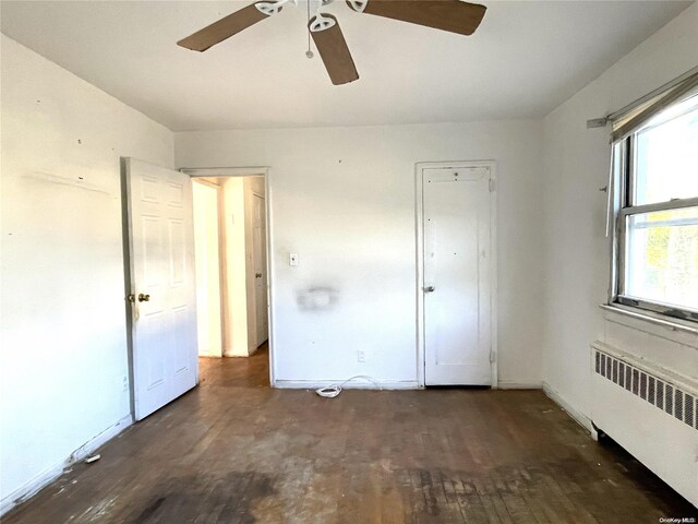 unfurnished bedroom featuring baseboards, radiator, wood finished floors, and a ceiling fan