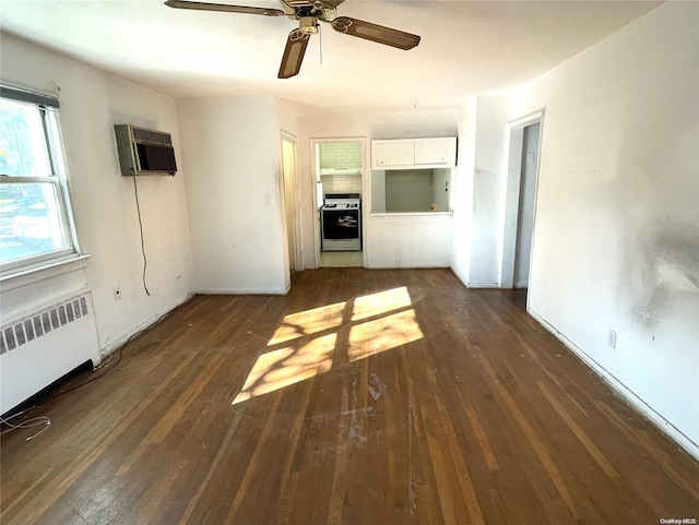 unfurnished living room with a wall mounted air conditioner, dark wood-type flooring, radiator, and a ceiling fan