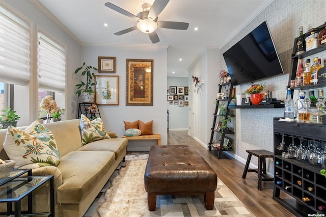 living room with ceiling fan, light hardwood / wood-style floors, crown molding, and indoor bar