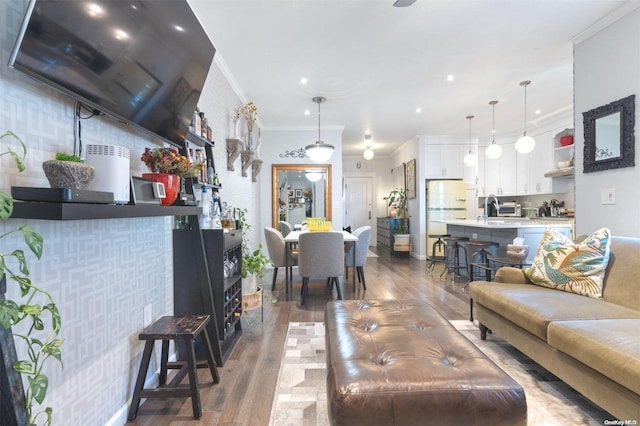 living room featuring dark hardwood / wood-style flooring, ornamental molding, and sink