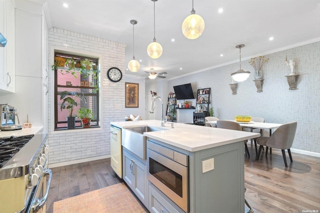 kitchen with sink, pendant lighting, a center island with sink, hardwood / wood-style flooring, and white cabinetry