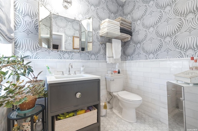 bathroom featuring vanity, tile walls, and toilet