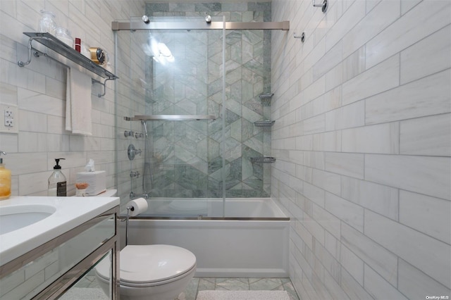 full bathroom featuring combined bath / shower with glass door, tile patterned floors, vanity, tile walls, and toilet